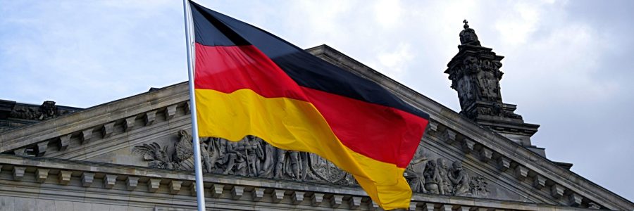 German national flag waving in front of the Reichstag building in Berlin, a symbol of democracy.